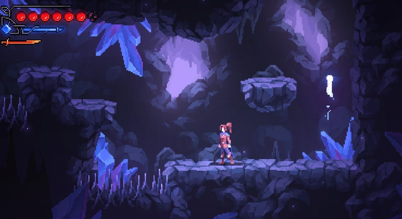 The protagonist scales a cliff face inside a dark, spike-filled cavern.